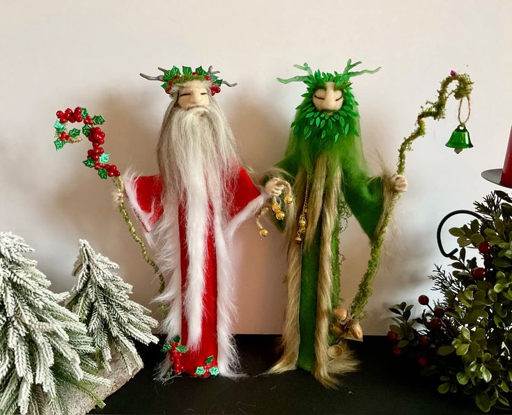 Two handmade dolls stand together. One is red and white, symbolizing the Holly King, and the other is green, symbolizing the Oak King.